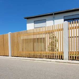 Quadratzaun aus Lärche mit Granitsäulen vor einem Neubau