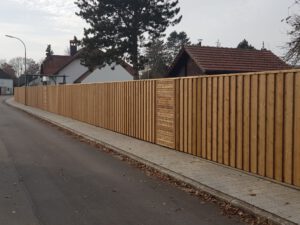 Hohe Sichtschutzwand aus Holz in einem älteren Baugebiet