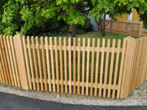 Quadratzaun aus Holz mit Holzpfosten umrandet Garten mit Bäumen